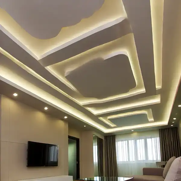 A modern living room with a pop ceiling design featuring layered gypsum board shapes